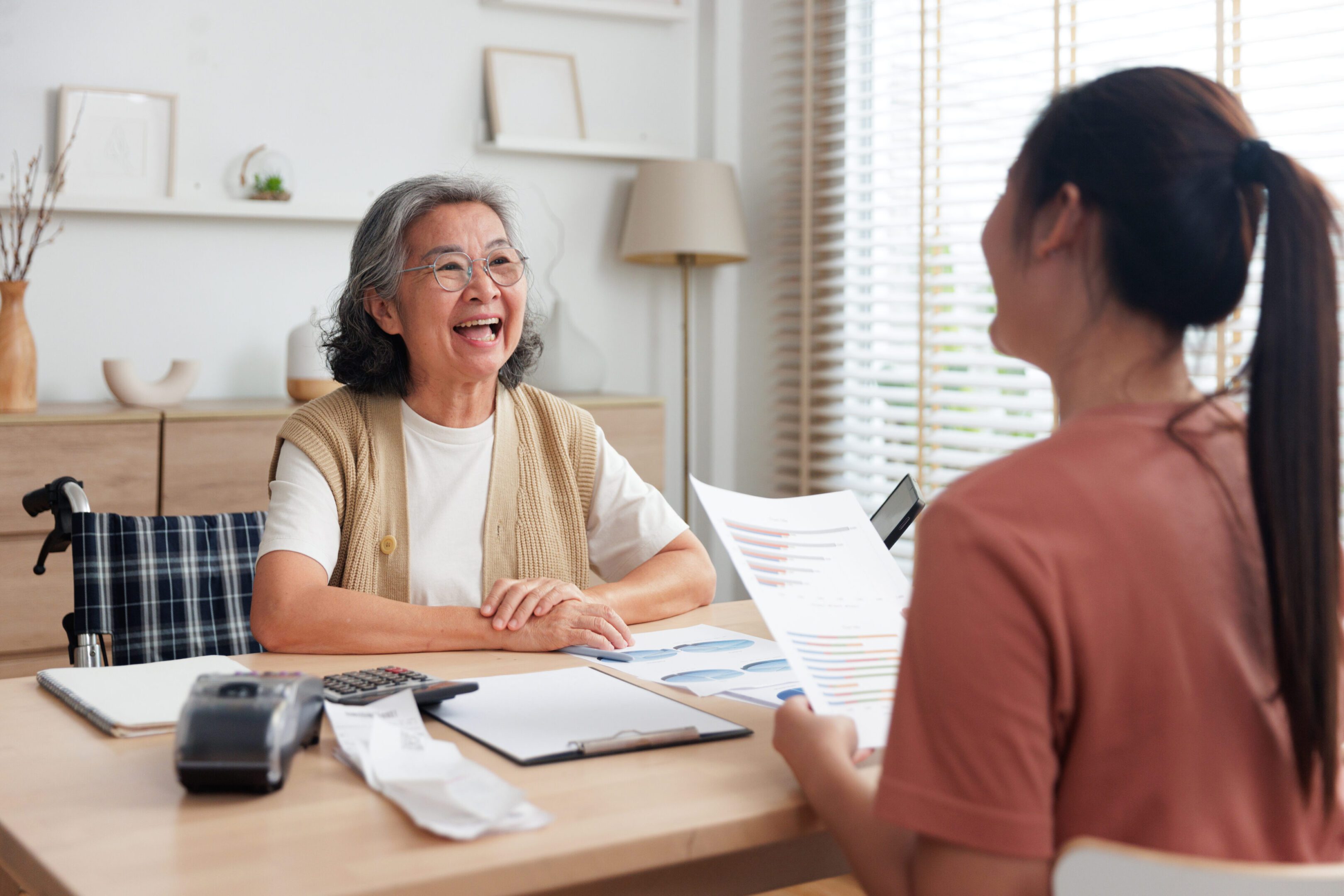 Two women engaging in a cheerful conversation at a table with documents.