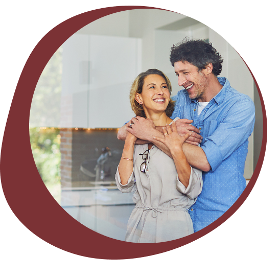 A happy couple embraces in a modern kitchen, sharing a joyful moment.