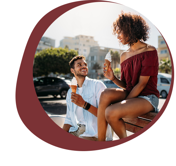 Couple enjoying ice cream together outdoors on a sunny day.