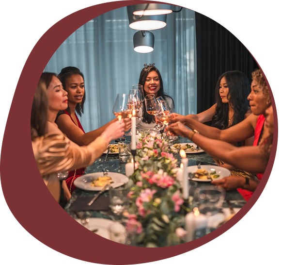 Friends enjoying a festive dinner with a toast around a beautifully decorated table.